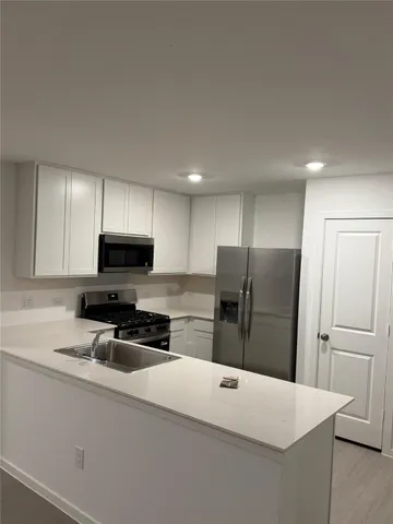 a kitchen with stainless steel appliances a refrigerator sink and white cabinets