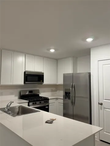 a kitchen with a refrigerator a microwave a sink and cabinets