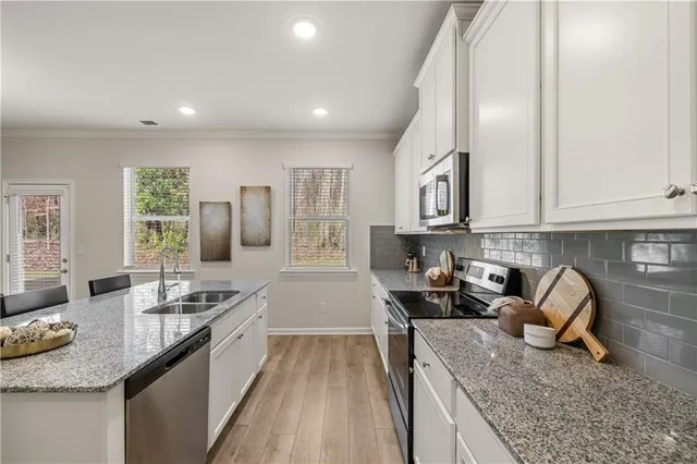 a kitchen with granite countertop stainless steel appliances sink stove microwave and cabinets