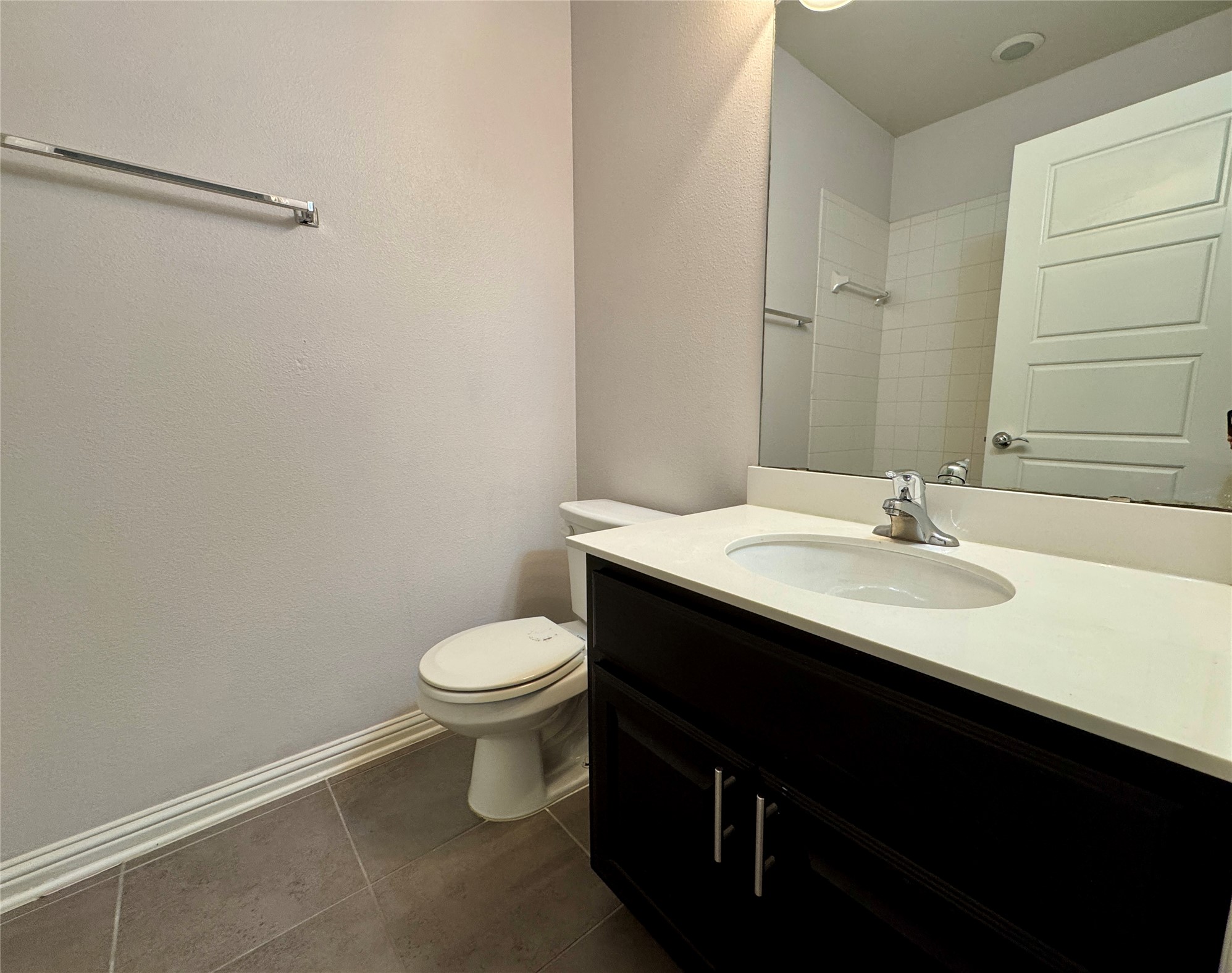 6814 East Riverside Drive, Unit 25 Austin, TX 78741 - Photo 16 of 26 Bathroom with vanity, dark tile patterned floors, a tile shower, and a textured wall