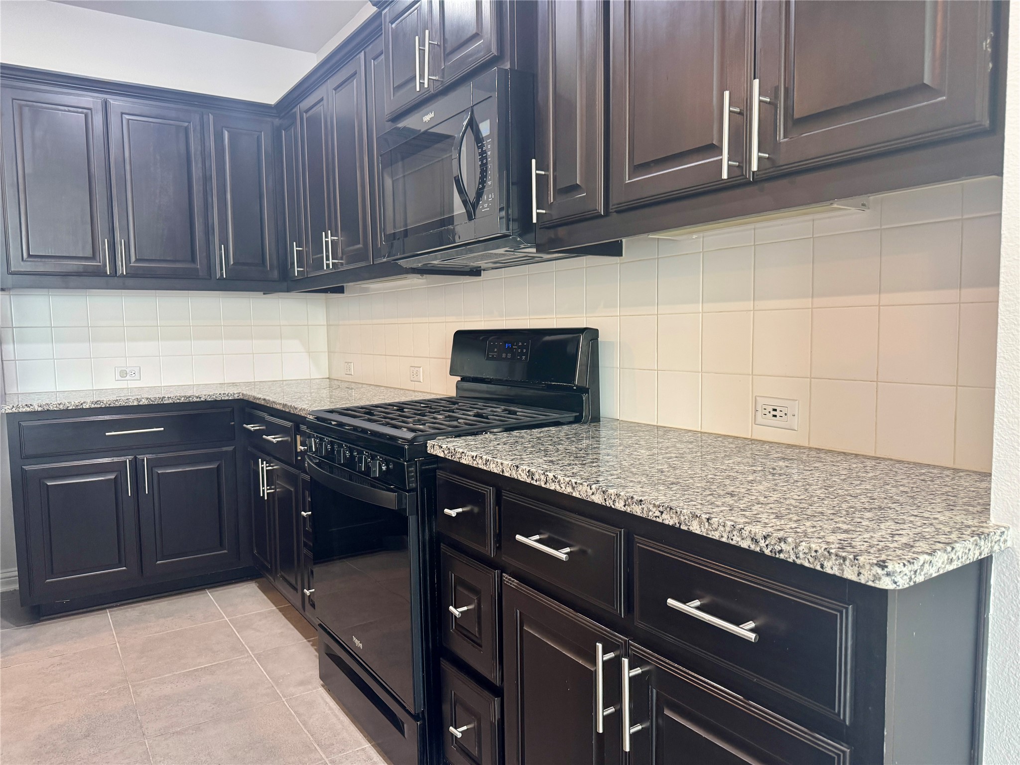 6814 East Riverside Drive, Unit 25 Austin, TX 78741 - Photo 7 of 26 Kitchen featuring black appliances, light tile patterned floors, backsplash, and light stone counters