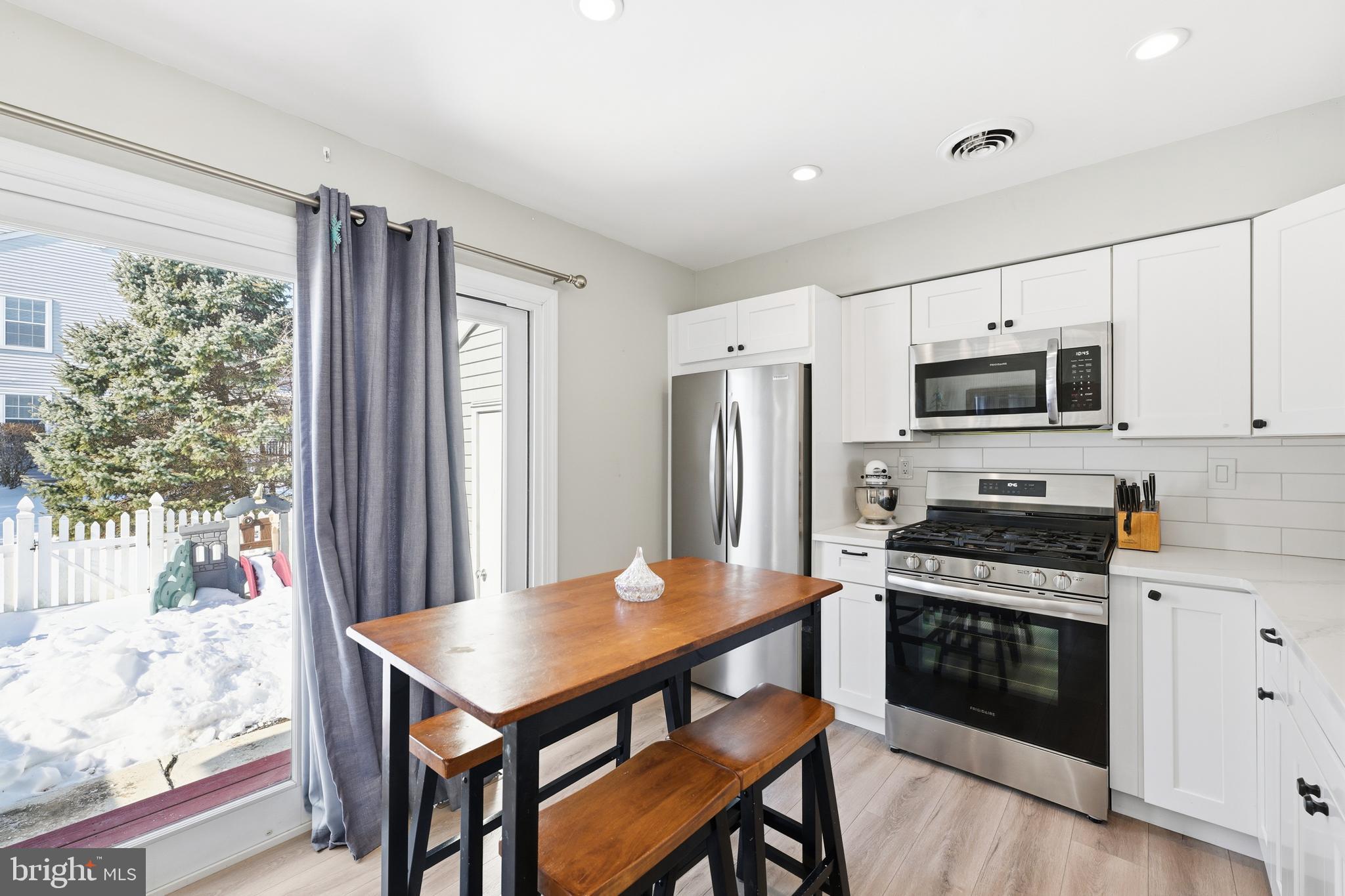 55 Violet Lane Newtown, PA 18940 - Photo 4 of 24 a kitchen with stainless steel appliances a stove a refrigerator a stove a microwave oven with a dining table and chairs