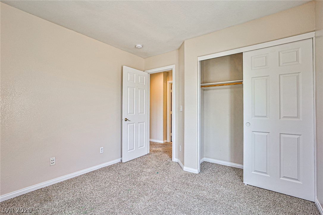 8022 Diamond Gorge Road Las Vegas, NV 89178 - Photo 19 of 37 Neutral walls and textured carpeting frame a classic bedroom complete with a sliding closet.