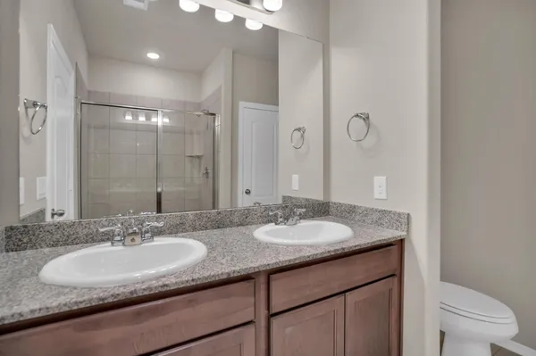 a bathroom with a granite countertop sink a toilet a mirror and shower