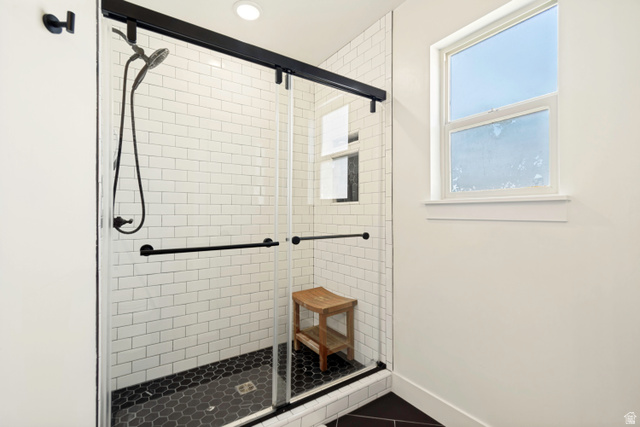 983 West 1550th Street South Springville, UT 84663 - Photo 26 of 43 Large walk-in shower with clear glass enclosure, black hardware, white subway tile surround, and black hexagonal floor tile.