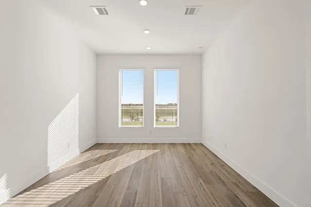 an empty room with wooden floor and windows