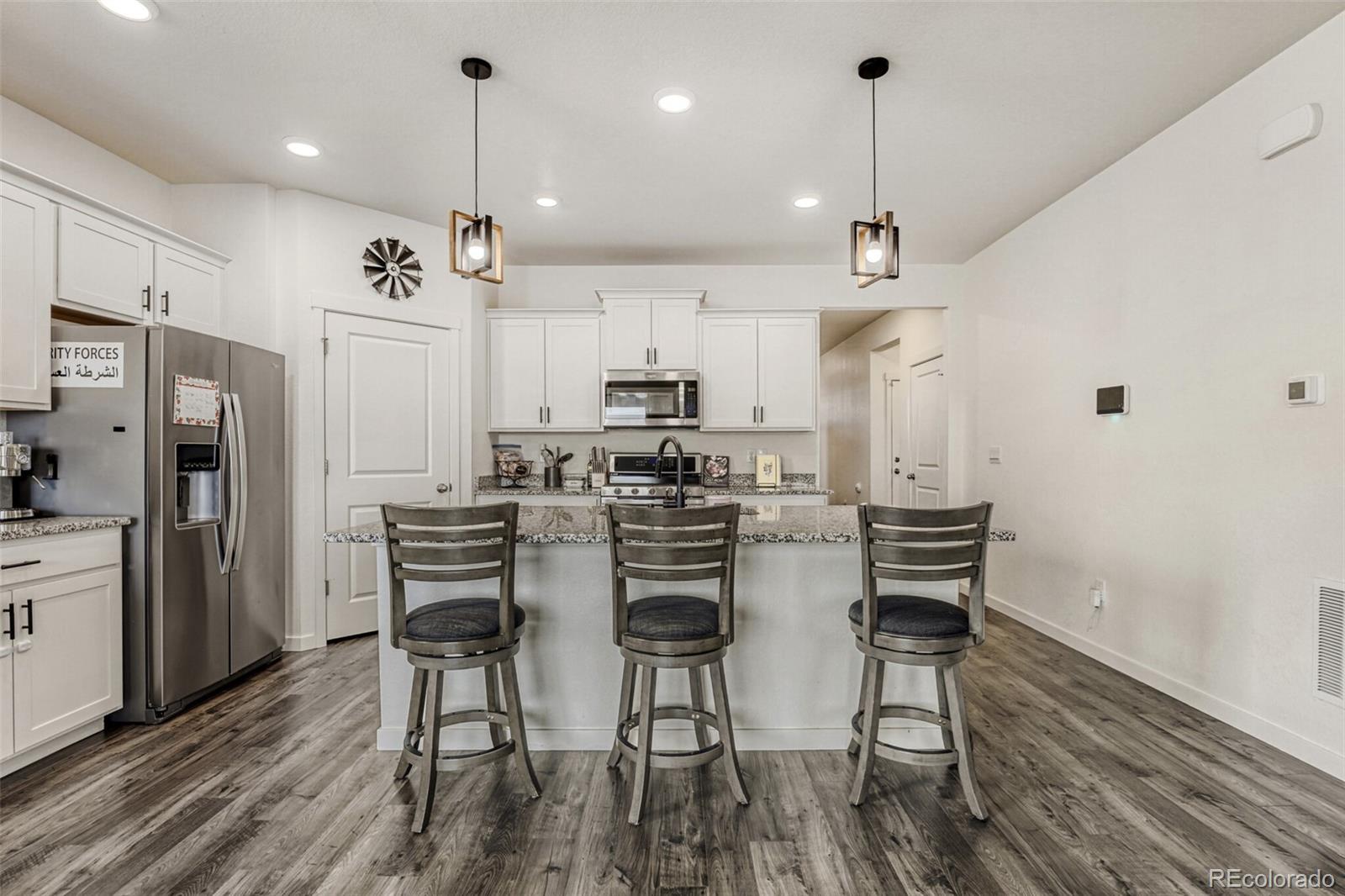 166 Racer Street Bennett, CO 80102 - Photo 12 of 44 a view of a dining room and livingroom with furniture wooden floor kitchen chandelier