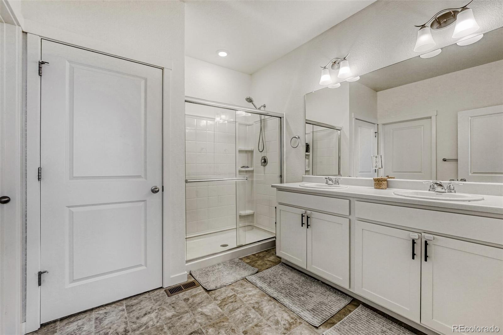 166 Racer Street Bennett, CO 80102 - Photo 24 of 44 a bathroom with a double vanity sink mirror and shower