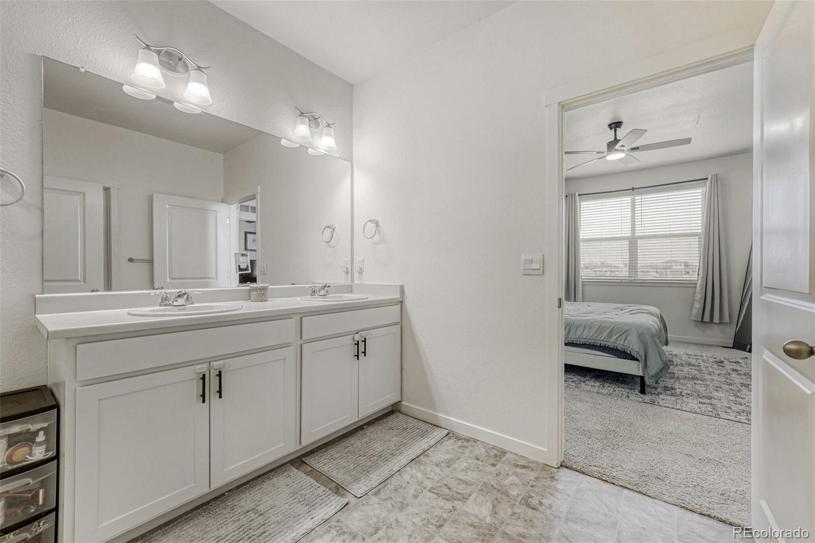 166 Racer Street Bennett, CO 80102 - Photo 25 of 44 a spacious bathroom with a double vanity sink and a mirror