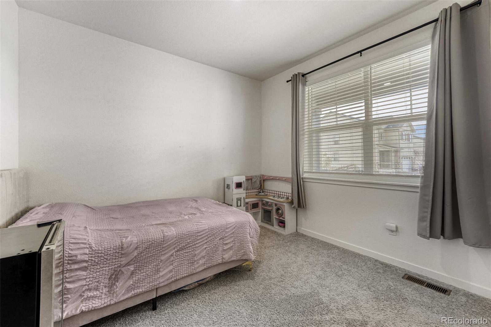 166 Racer Street Bennett, CO 80102 - Photo 26 of 44 a bedroom with a bed and a table next to a window