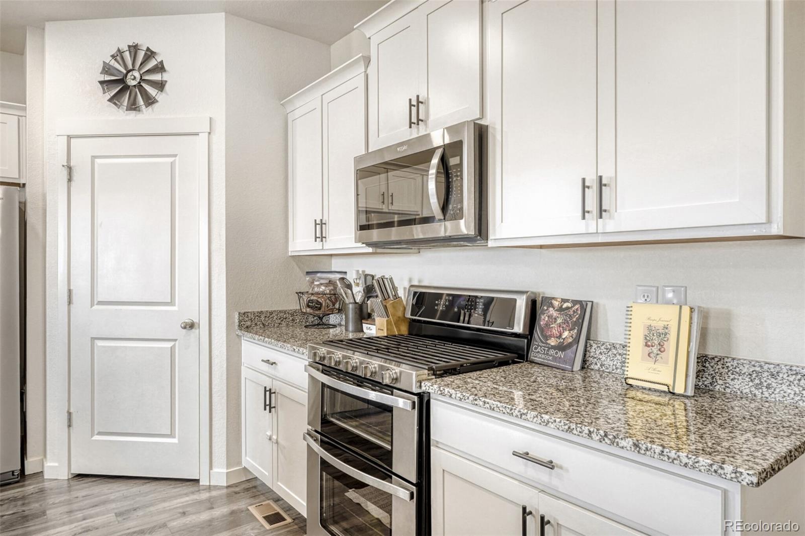 166 Racer Street Bennett, CO 80102 - Photo 9 of 44 a kitchen with granite countertop a sink stainless steel appliances and cabinets