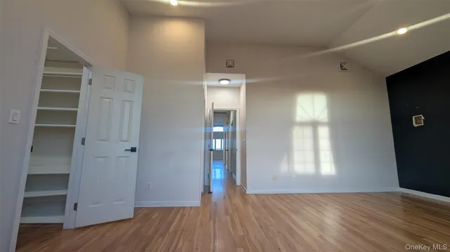 a view of an empty room with wooden floor and closet