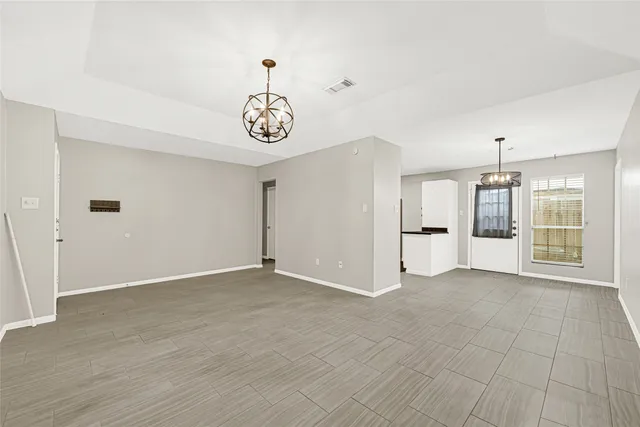 an empty room with windows and refrigerator