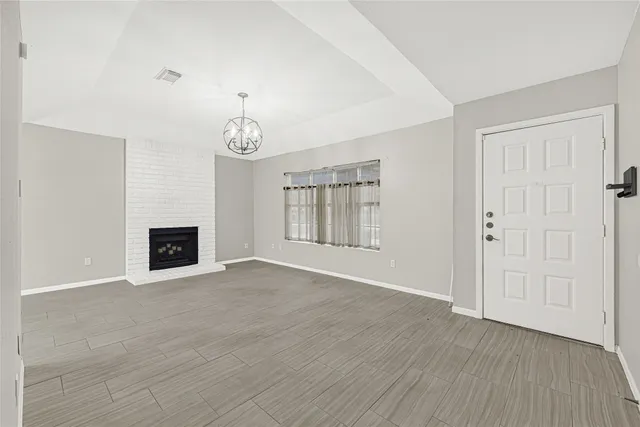 an empty room with wooden floor fireplace and windows