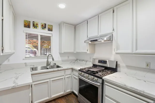 a kitchen with stainless steel appliances white cabinets and a stove top oven