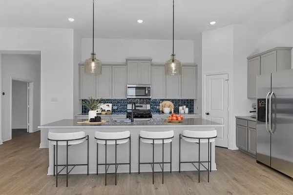 a kitchen with stainless steel appliances kitchen island granite countertop a dining table chairs refrigerator and microwave
