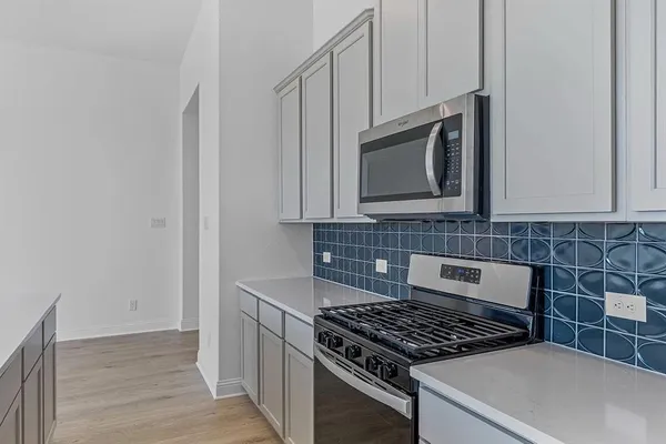 a kitchen with granite countertop white cabinets stainless steel appliances and wooden floor