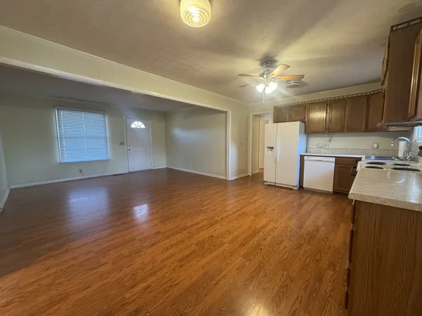 a view of an empty room with window and wooden floor