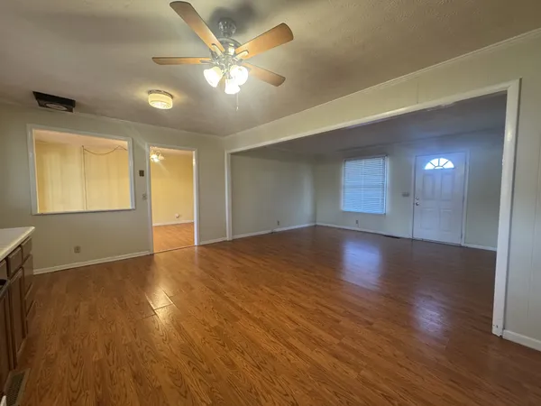 a view of an empty room with window and wooden floor