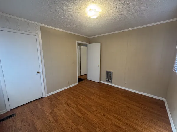 a view of an empty room with wooden floor and closet