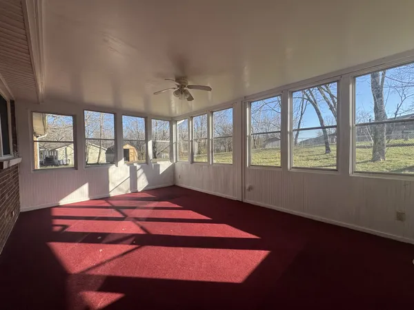 a view of empty room with wooden floor and kitchen