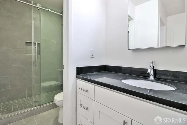 a bathroom with a granite countertop sink a toilet and shower