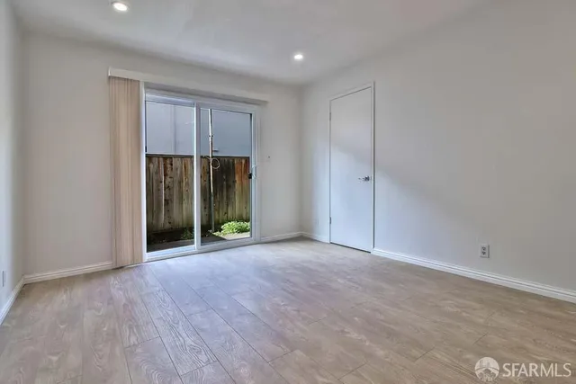 a view of an empty room with wooden floor and entryway