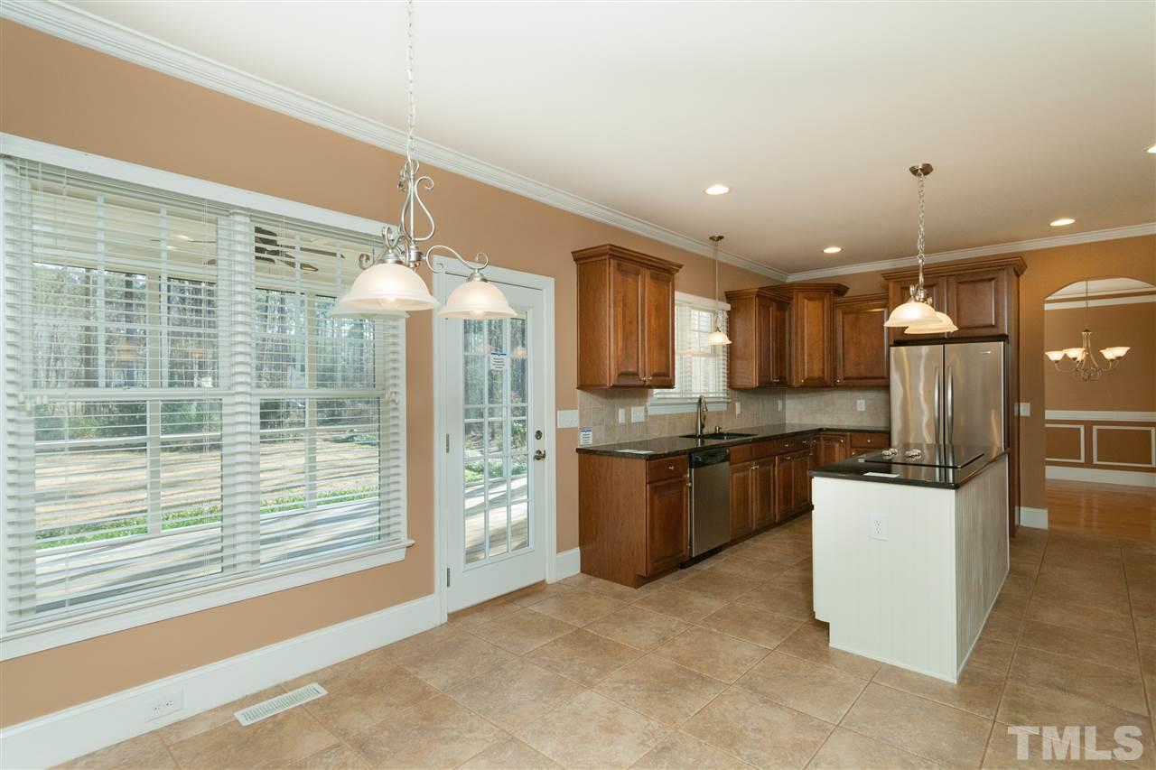 7217 Duncans Ridge Way Fuquay-Varina, NC 27526 - Photo 9 of 25 a kitchen with stainless steel appliances kitchen island granite countertop a refrigerator a stove and a sink with wooden floor