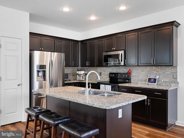 a kitchen with granite countertop a stove sink and refrigerator