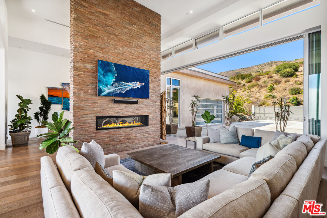 10715 Yerba Buena Road Malibu, CA 90265 - Photo 11 of 32 a living room with furniture a fireplace and a floor to ceiling window
