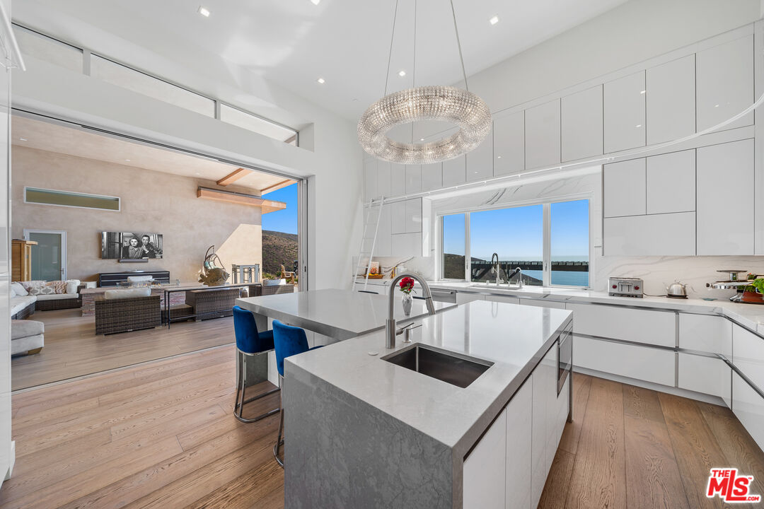 10715 Yerba Buena Road Malibu, CA 90265 - Photo 13 of 32 a kitchen with a stove a sink dishwasher a refrigerator and white cabinets with wooden floor