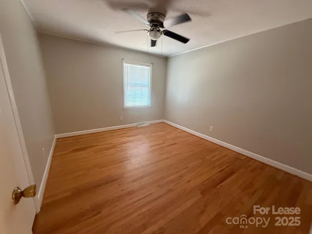 an empty room with a window and a ceiling fan
