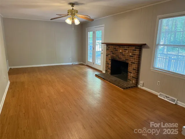 an empty room with wooden floor fireplace and windows