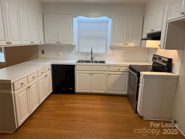 a kitchen with stainless steel appliances granite countertop a stove a sink and white cabinets