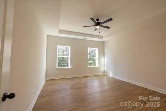 a view of empty room with wooden floor and fan
