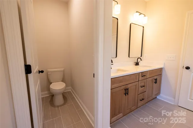 a bathroom with a double vanity sink toilet and a mirror