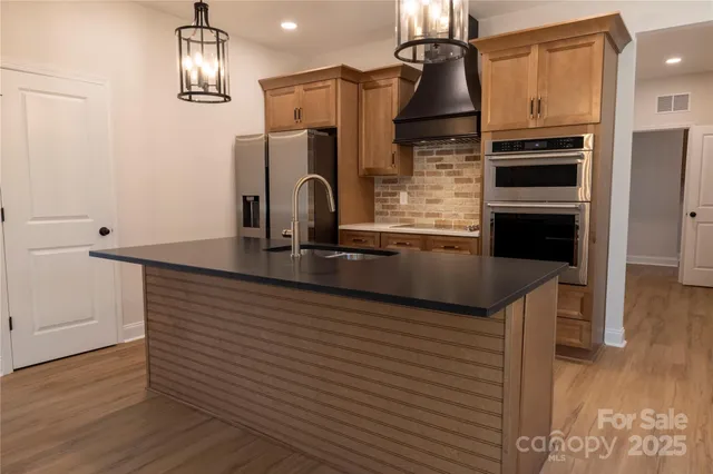a kitchen with granite countertop stainless steel appliances and wooden floor