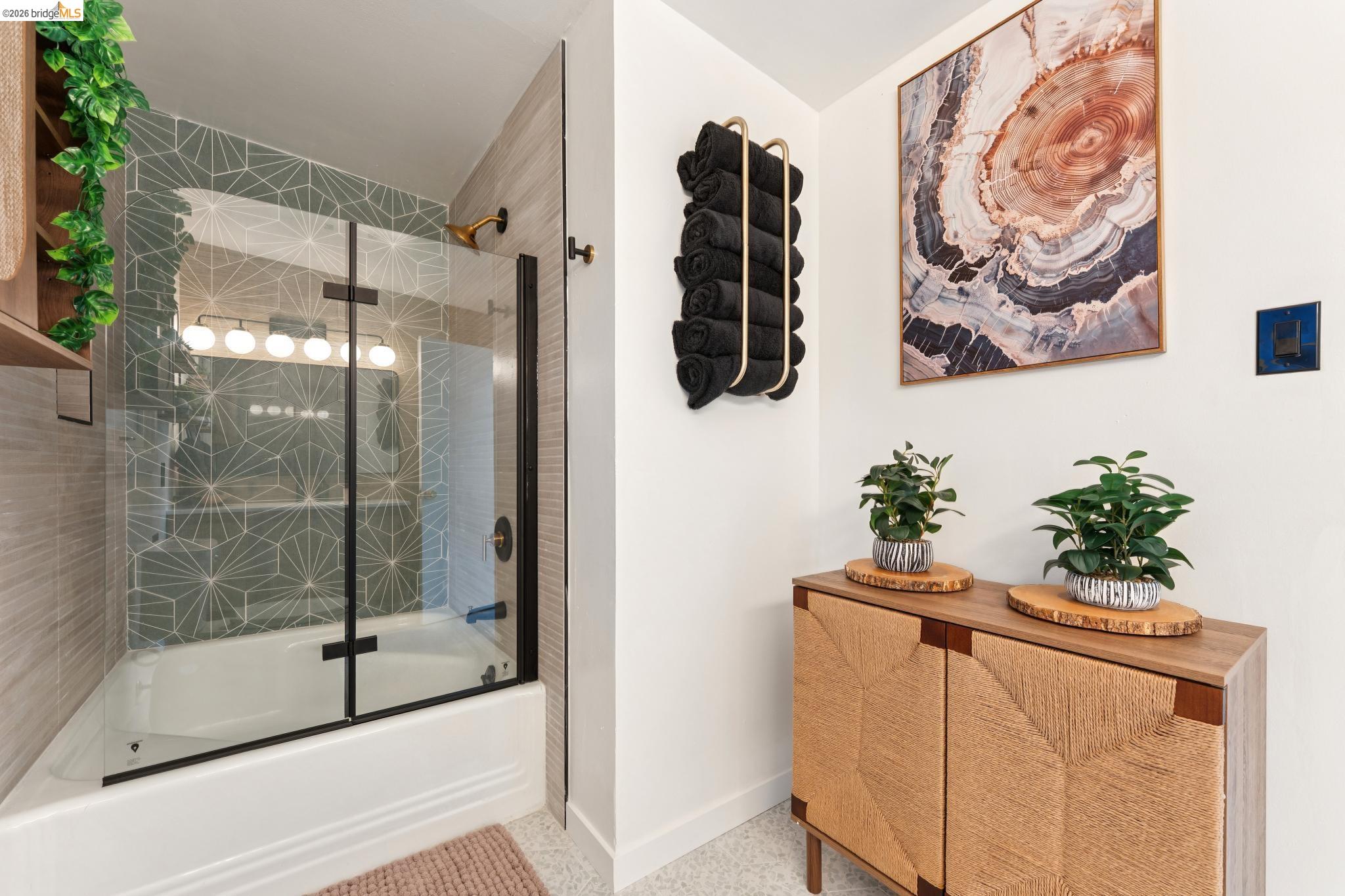 2301 Oak Street Berkeley, CA 94708 - Photo 24 of 61 Full-size bathtub with a clear glass enclosure and black trim, featuring geometric-patterned wall tile and a gold-tone shower head