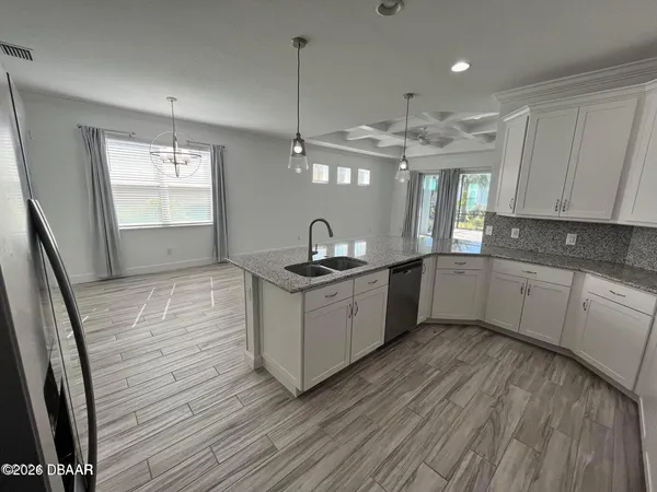a kitchen with a sink dishwasher a refrigerator and white cabinets with wooden floor