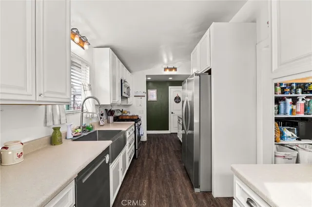 a kitchen that has a lot of cabinets a sink and wooden floor