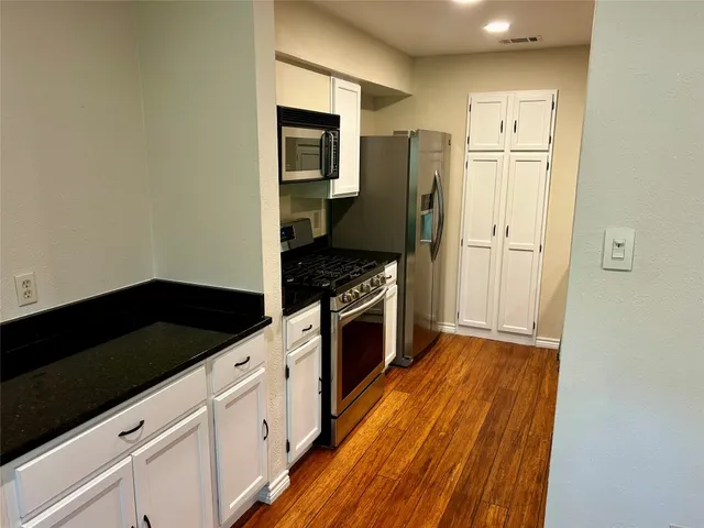 a kitchen with granite countertop a refrigerator stove and sink