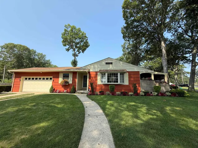 a front view of a house with a garden and trees