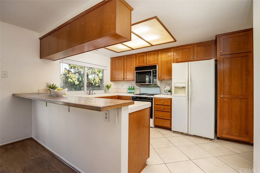 7951 Waterfall Circle Huntington Beach, CA 92648 - Photo 10 of 40 a kitchen with stainless steel appliances granite countertop a sink a stove a refrigerator a washer dryer and white cabinets