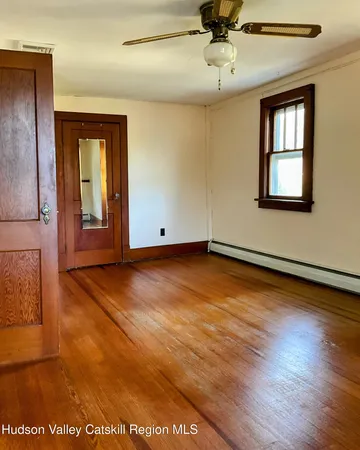 an empty room with wooden floor cabinet and windows