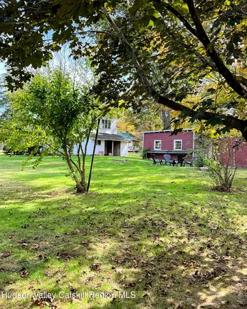 a view of a house with a big yard and large trees
