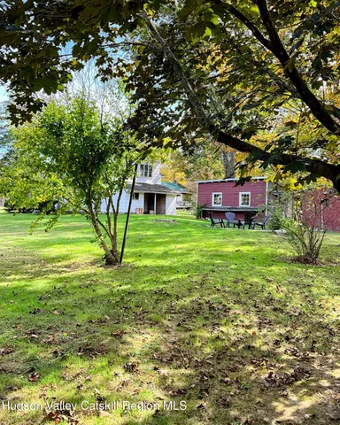 a view of a house with a big yard and large trees