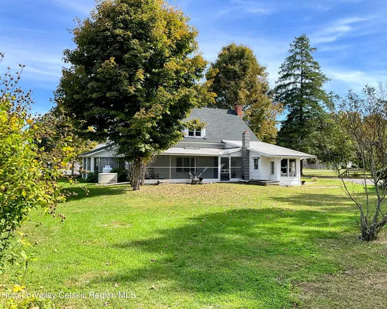 a view of a house with a yard plants and large tree