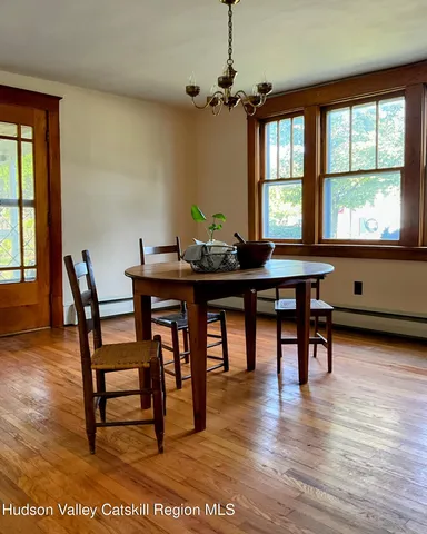 a view of a a dining room with furniture window and wooden floor