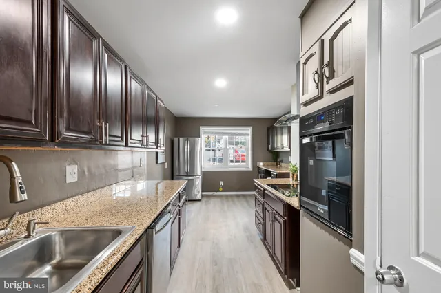 a kitchen with granite countertop stainless steel appliances a sink stove top oven and cabinets