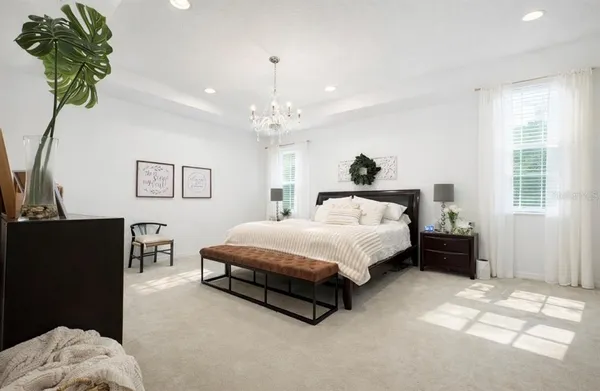 a spacious bedroom with a bed chandelier and a window